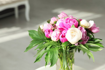 Vase with bouquet of beautiful peonies in room, space for text
