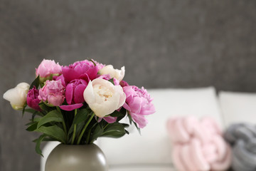 Vase with bouquet of beautiful peonies in room, space for text