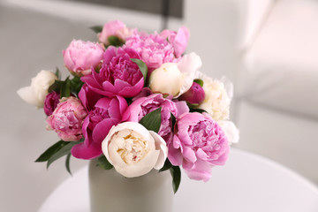 Vase with bouquet of beautiful peonies on table in room, space for text