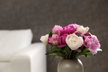 Vase with bouquet of beautiful peonies in room, space for text