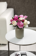 Vase with bouquet of beautiful peonies on table in room