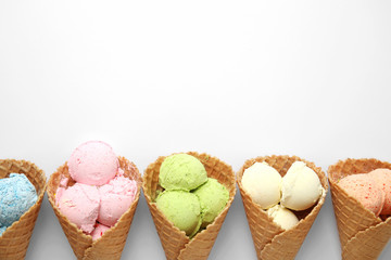 Composition with delicious ice creams in waffle cones on white background, top view