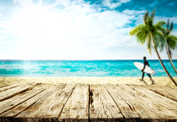 Desk of free space and summer blurred background of beach with surfers 