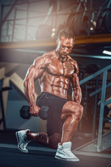 Fototapeta na wymiar Muscular Man Doing Dumbbell Lunges at the Gym