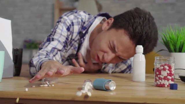 young asian man in a shirt asthmatic with attacks of suffocation uses an inhaler slow mo
