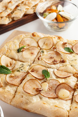 Close up of roman sweet pizza with nuts, pear and honey, baked in coal stove for dessert, served with other italian snacks