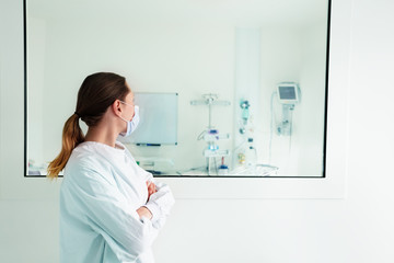 Doctor looking through hospital glass in ICU