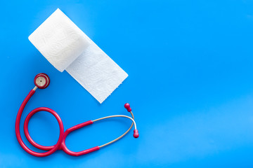Disease of colon concept with toilet paper roll and stethoscope on blue background top view space...