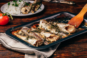 Baked fish carcasses on baking sheet over wooden surface