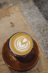 cup of coffee with cream on wooden background