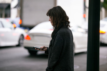 Female pedestrian waiting for a rideshare.  She is sharing her gps location via cellphone app so...
