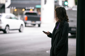 Female pedestrian waiting for a rideshare.  She is sharing her gps location via cellphone app so...