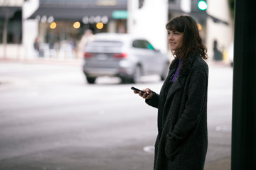 Female pedestrian waiting for a rideshare.  She is sharing her gps location via cellphone app so...