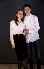 The guy hugs a girl in strict clothes, studio monophonic background
