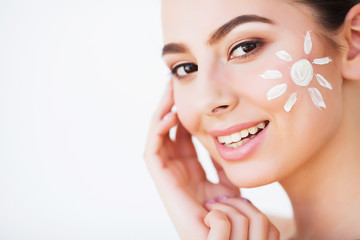 Sun Tanning. Beauty Girl Applying Sun Tan Cream on her Face.