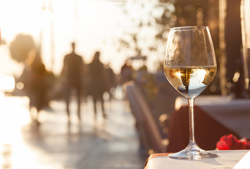 Glass of chilled white wine over sunset city background