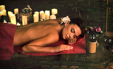 Young woman on massage in spa salon on light candels background.