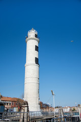 Fototapeta na wymiar Laguna brick buildings and lighthouse of Murano in Venice in Italy,2019.