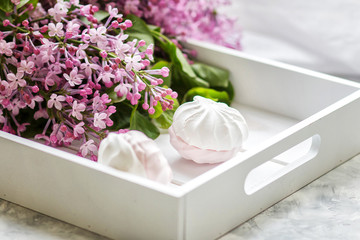 The handmade marshmallows served in a gift box and a bouquet of a lilac. Close up.