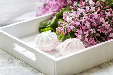 The handmade marshmallows served in a gift box and a bouquet of a lilac. Close up.