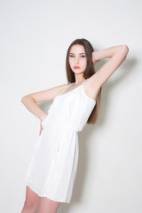 woman in white dress stans with hand up