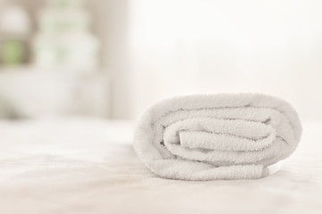 white folded towel on bed in daylight in hotel