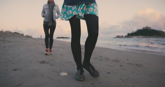 Two young women walking on the beach