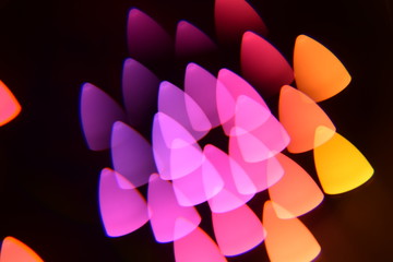 Multicolored spots in the form of a mediator on a black background. Multicolored bright big bokeh beautifully glow on a black background. copy space