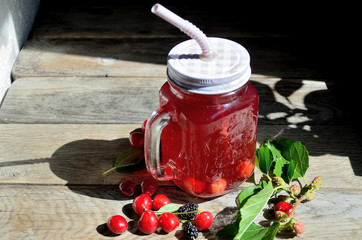 Compote of cherry and mulberry on a wooden table, sunny day.