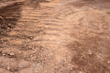 Wheel indentation left by heavy vehicles passing through red clay pavement