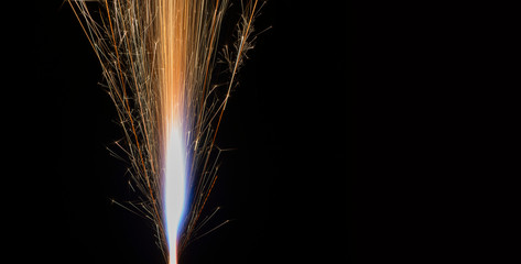 Shot of yellow gunpowder sparks shooting upwards on black background