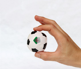 Fototapeta premium Mini ball of football in hand and one black point of football is Algeria flag, hold it with two finger on white background.