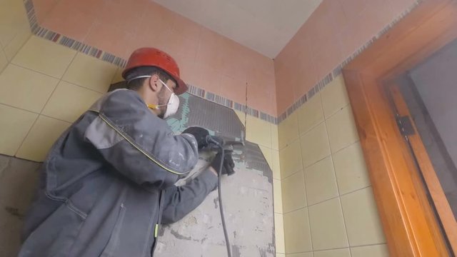 Demolition of old tiles with jackhammer. Renovation of old walls in the bathroom or kitchen