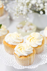 Vanilla cupcakes with cream cheese frosting on a white cake stand