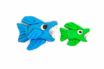 Play dough big fish eat little fish on white background. Handmade clay plasticine