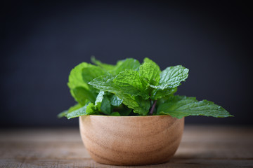 peppermint leaf in a wood bowl - Fresh mint leaves on dark background