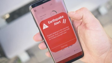 Receiving an EARTHQUAKE warning notification on a smartphone screen. Blinking alert concept