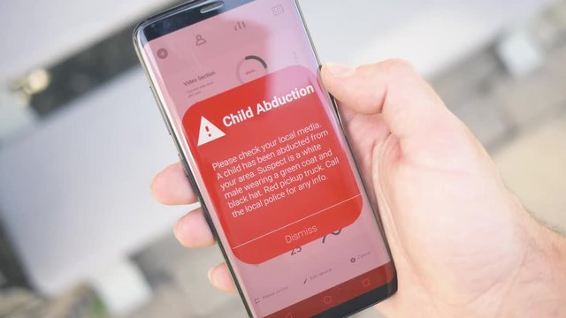 Receiving a CHILD ABDUCTION warning notification on a smartphone screen. Blinking alert concept
