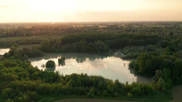 4K Aerial : Cinematic spotlight shot over a natural lake with clouds reflected inside in a rural landscape