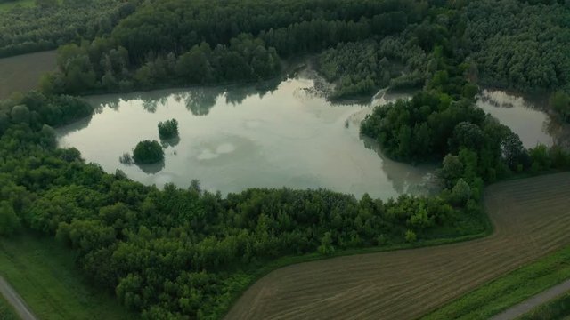 4K Aerial : Cinematic spotlight shot over a natural lake in a typical italian rural lanscape