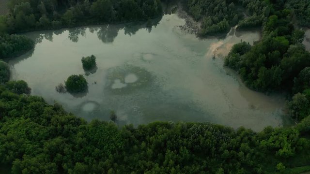 4K Aerial : Cinematic revealing shot of a country landscape with a reflective natural lake