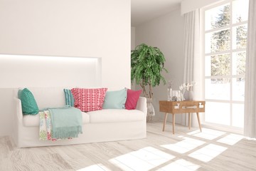 Fototapeta premium Stylish room in white color with sofa and winter landscape in window. Scandinavian interior design. 3D illustration