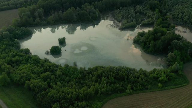 4K Aerial : Fast Cinematic revealing shot of a country landscape with a reflective natural lake