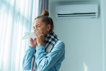 Sneezing woman caught a cold from the air conditioner at home. Conditioner disease - obrazy, fototapety, plakaty