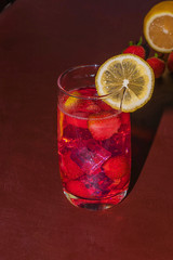 Drink with ice from strawberries on a dark background. Fresh strawberry cocktail. Fresh summer cocktail with strawberry and ice cubes. Glass of strawberry soda drink on dark background.