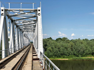 Railway bridge over the river against the blue sky.