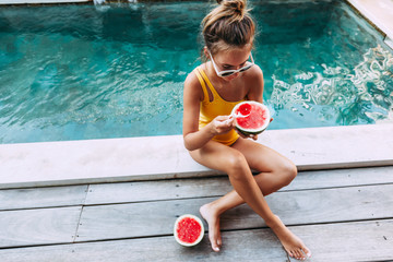 Girl eating watermelon in pool on luxury villa in Bali