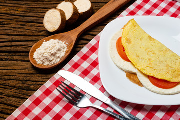 Crepioca. Pancake of cassava (tapioca) with cheese and tomato on plate on old wooden background. Selective focus.