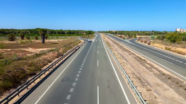 A time lapse shot of the AP7 motorway in Spain near Torrevieja in the sunshine and blue sky. Location on a highway bridge.