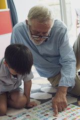 Fototapeta premium senior man happiness, smiling nurse and grandson are sitting on the floor and playing games at living room together